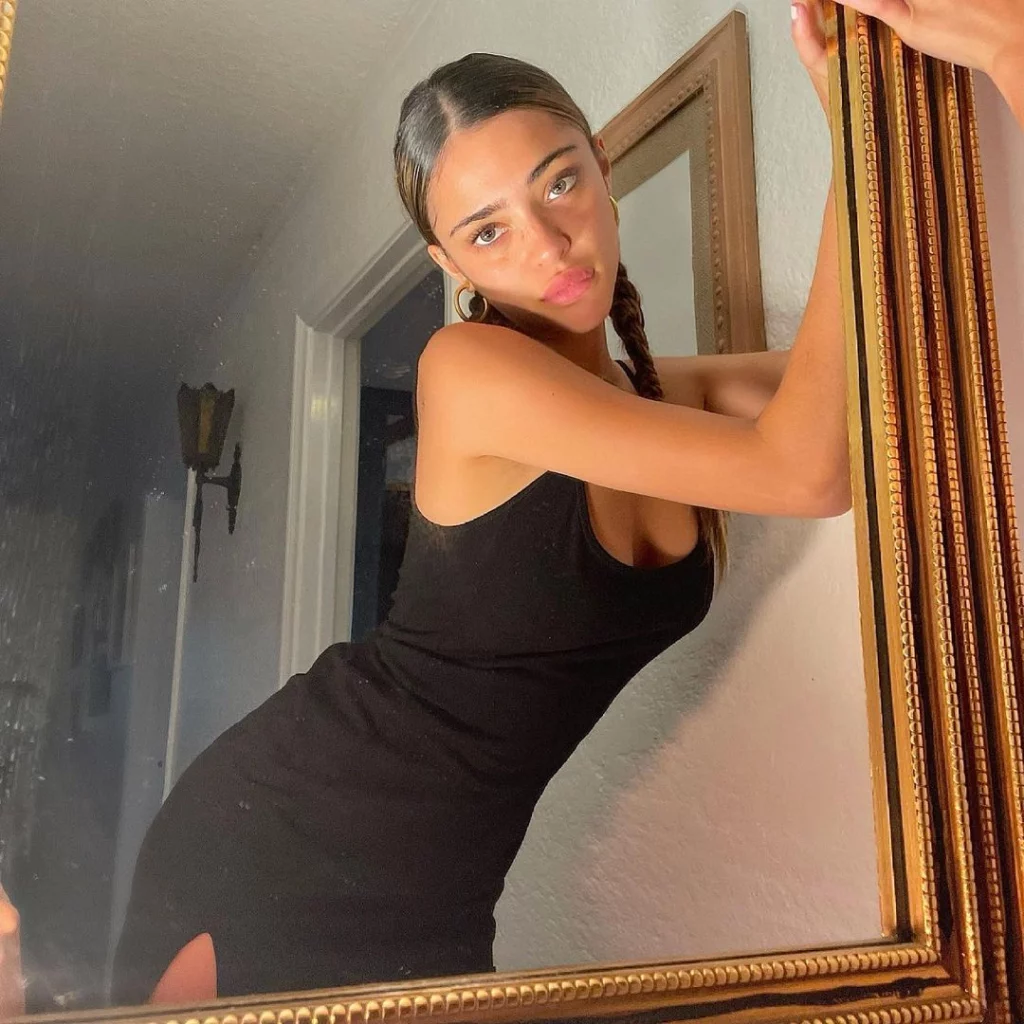 Blaise wearing a black dress posing in front of mirror