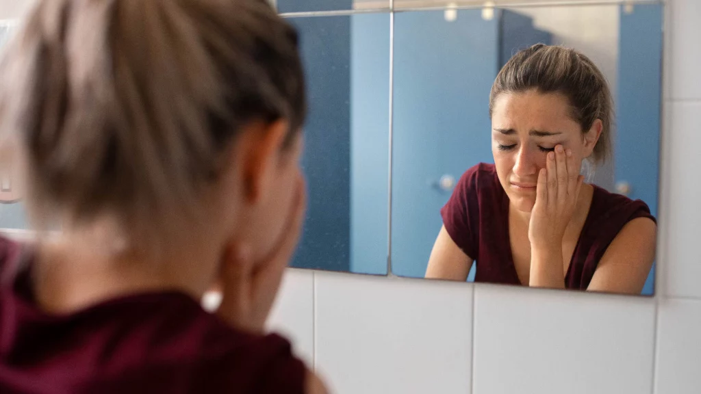 a girl crying in front of the mirror