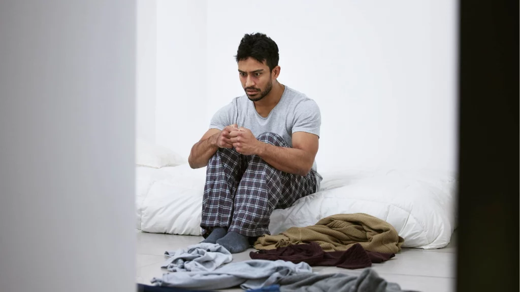 an afraid man sitting on his bed