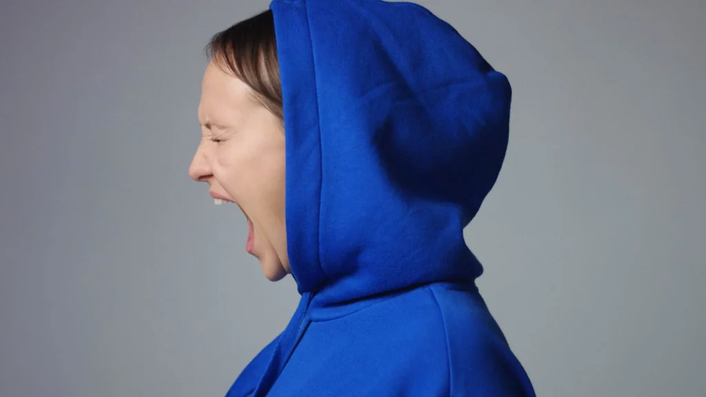 a girl wearing blue hoodie screaming 
