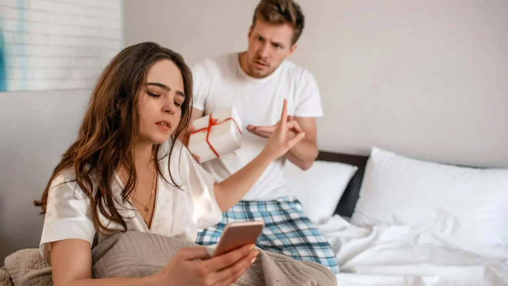 Girl using her phone and boy talking behind