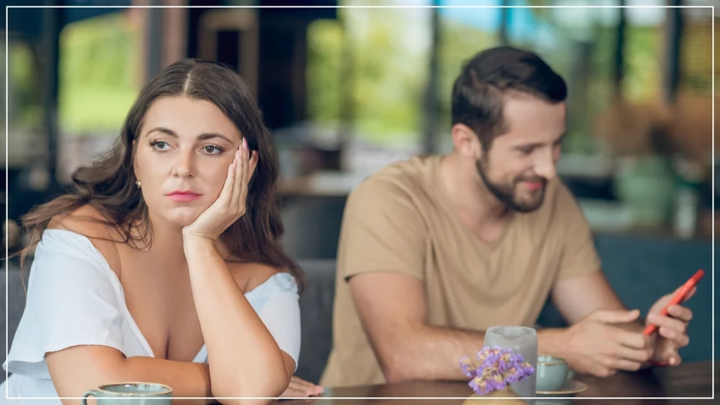 A girl sitting aside and boy texting on the phone