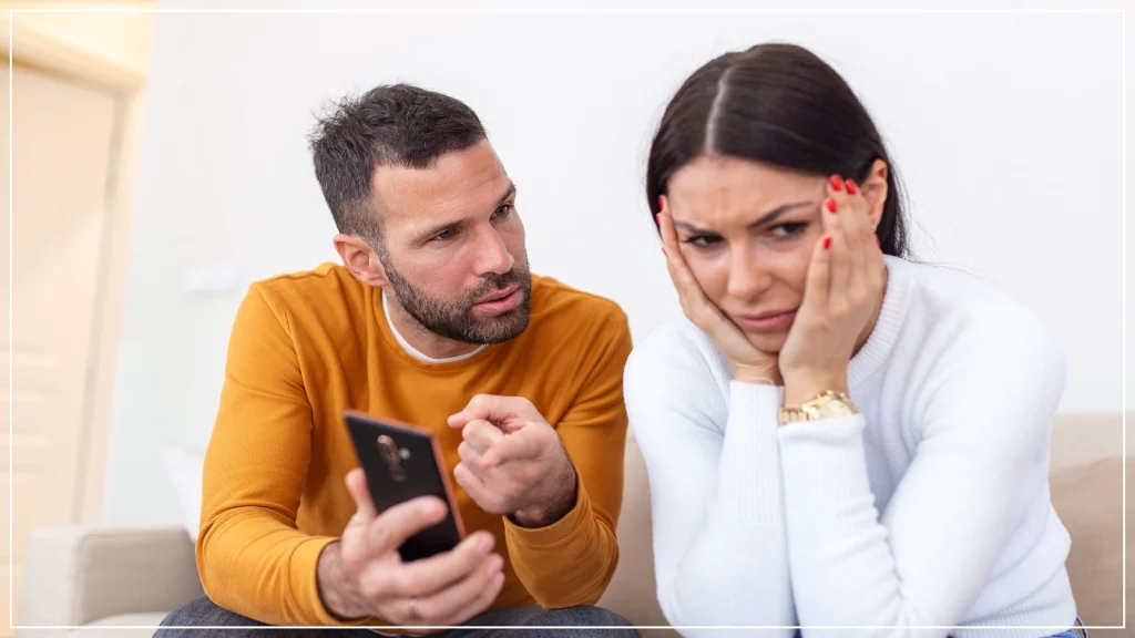Man showing something on his phone to a woman sitting beside her