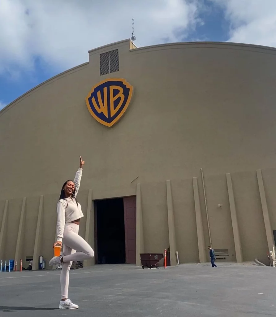 Netta wearing a white shirt and bottoms posing outside the studio of Warner Bros.