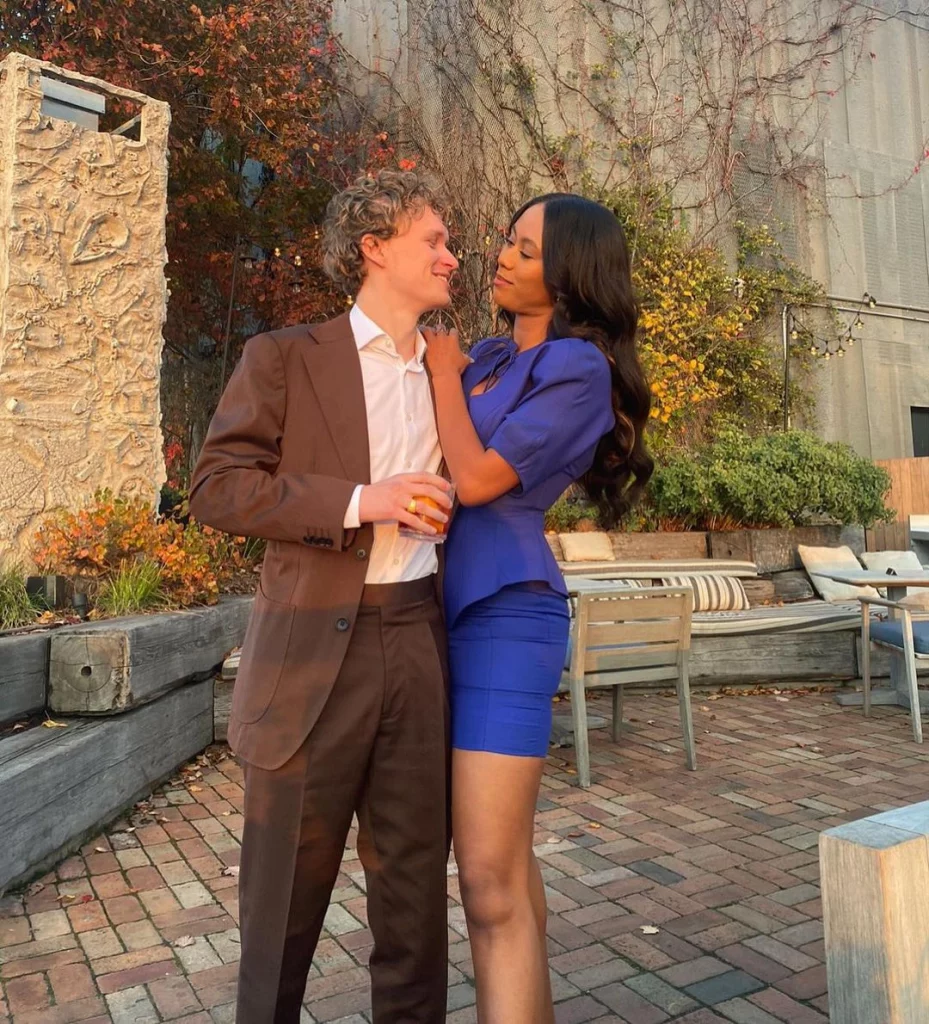 Netta Walker wearing a blue dress posing with her Boyfriend Jack, who is wearing a white shirt and brown colored suit.