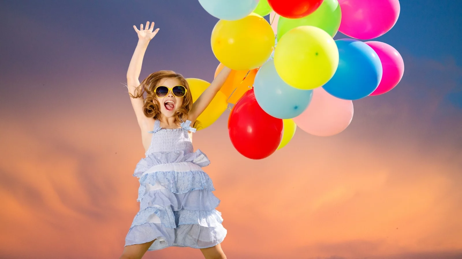 A girl jumping with balloons in hands. 