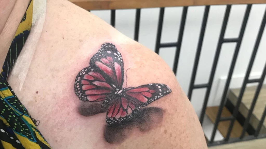 colored butterfly tattoo on back shoulder