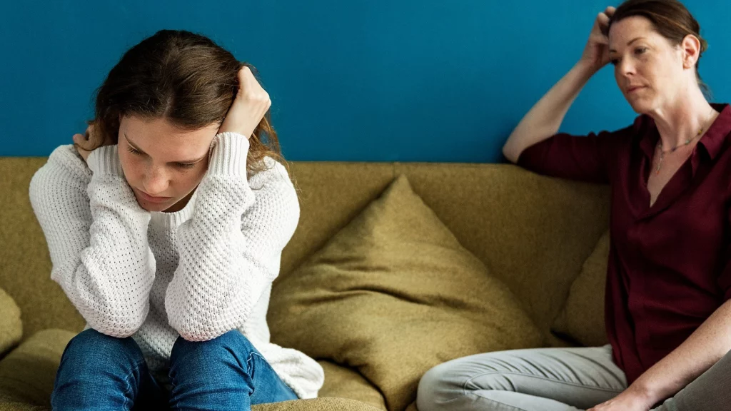 girl in white sweater holding her head