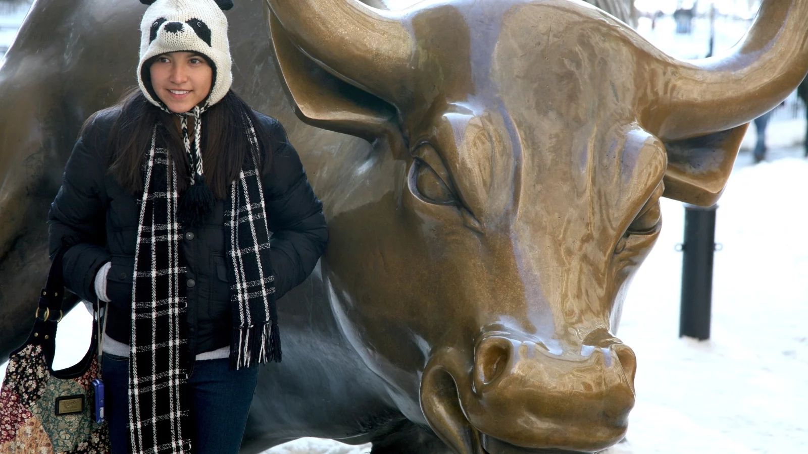 A tourist posing with the Wall Street Bull. 