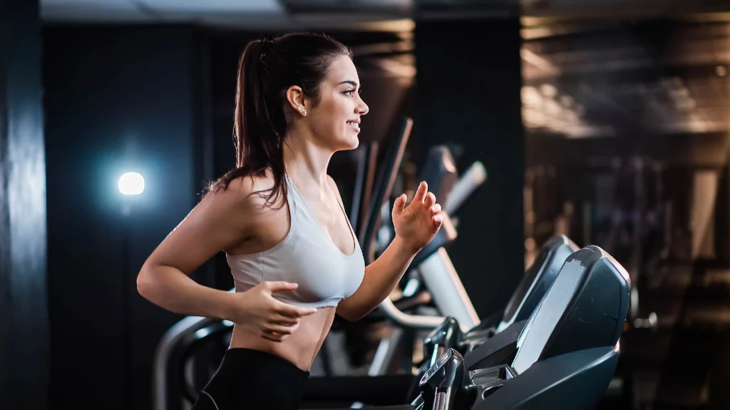 a girl walking on a treadmill in gym.