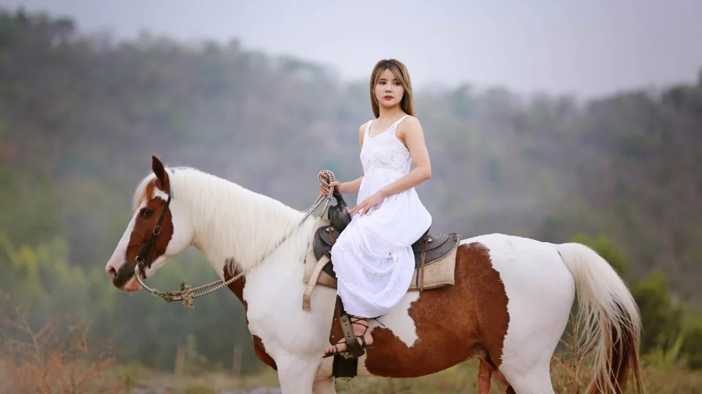 Girl in a white gown sitting on horse