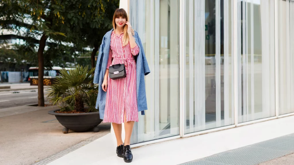 girl wearing a stripped dress with blue overcoat