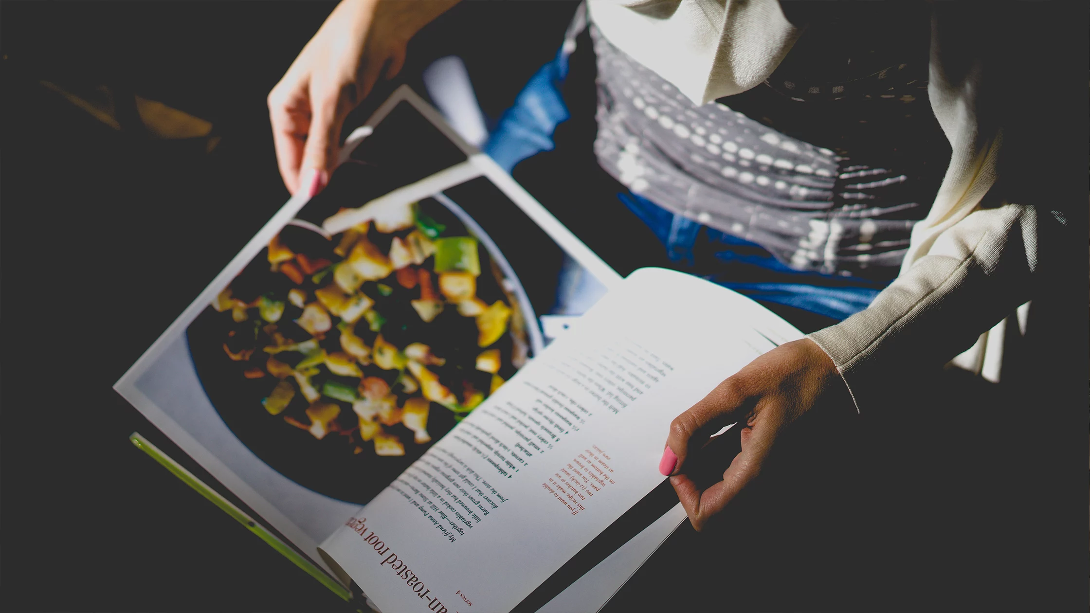 Girl reading recipes from a cook book. 