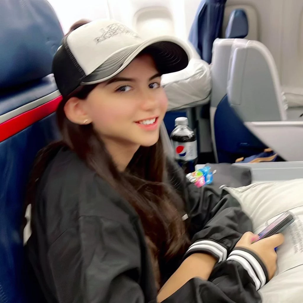 Madison wearing black jacket and white hat while traveling to New York.